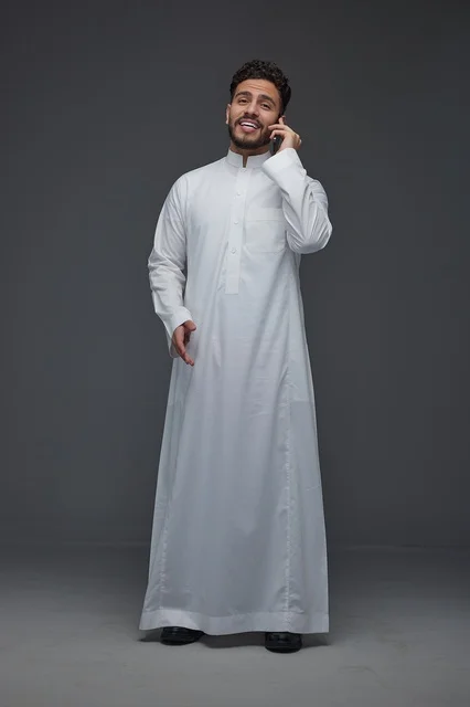 رجل سعودي بالثوب التقليدي يستخدم الهاتف الذكي في استوديو