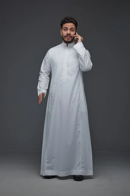رجل سعودي بالثوب التقليدي يتحدث عبر الهاتف الذكي