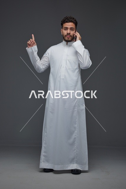 رجل سعودي بالثوب التقليدي يتحدث عبر الهاتف الذكي