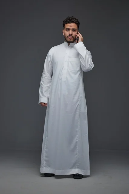 Saudi Man in Traditional White Thobe Talking on Smartphone
