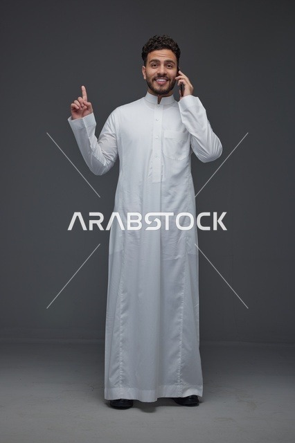 رجل سعودي يتحدث بالهاتف ويشير للأعلى بالثوب التقليدي