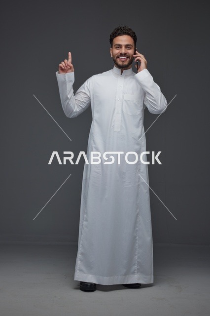 رجل سعودي بالثوب يتحدث بالهاتف الذكي في الاستوديو