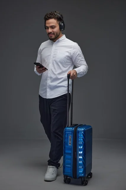 Saudi Traveler with Blue Suitcase and Smartphone in Studio