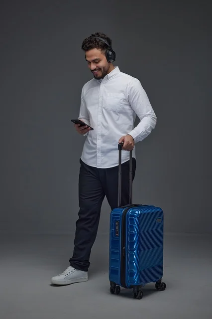 Saudi Traveler with Blue Suitcase and Smartphone
