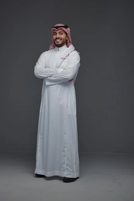 رجل سعودي بالزي التقليدي في استوديو بخلفية رمادية