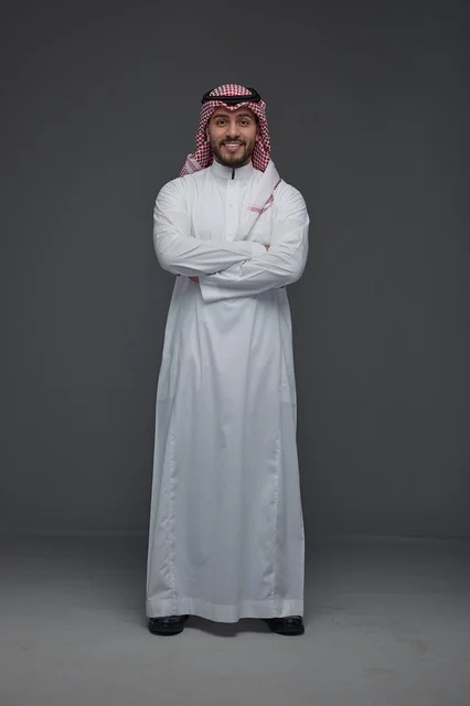 رجل سعودي مبتسم بالزي التقليدي في استوديو احترافي