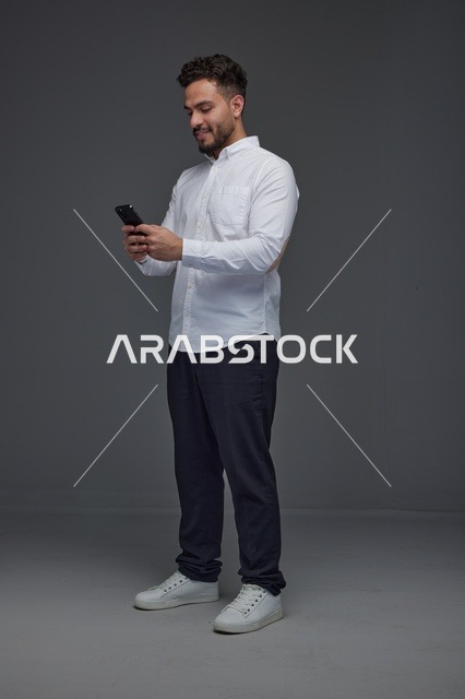 رجل سعودي يستخدم الهاتف الذكي بخلفية رمادية