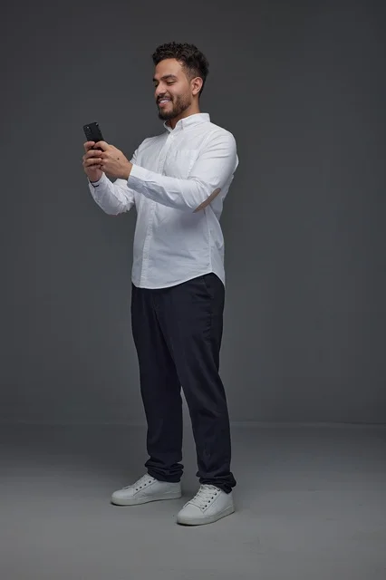 Saudi Man Using Smartphone on Grey Background Studio