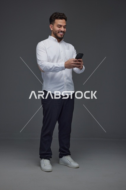 رجل سعودي يستخدم الهاتف الذكي بخلفية رمادية
