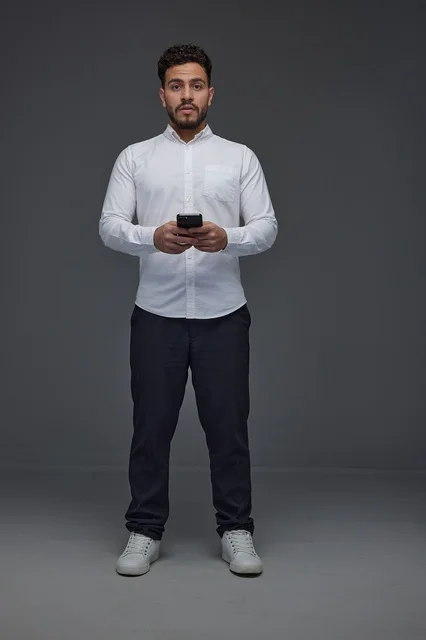 Saudi Man Holding Smartphone on Grey Studio Background