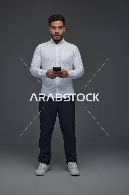 Saudi Man with Shocked Expression Holding Smartphone