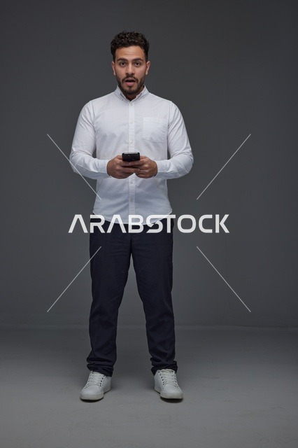 رجل سعودي يستخدم الهاتف الذكي بتعبيرات مندهشة