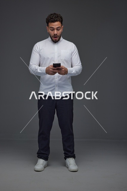رجل سعودي مندهش يستخدم الهاتف الذكي في الاستوديو