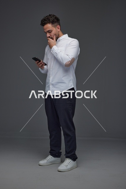 Saudi Man Thinking While Using Smartphone in Studio
