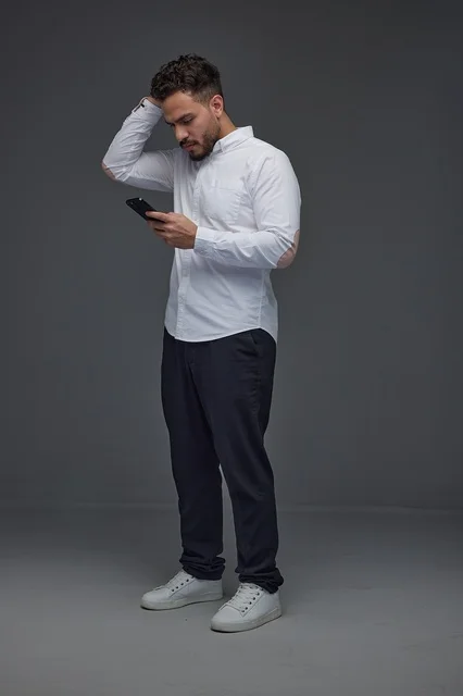 Saudi Man Looking at Smartphone on Grey Background