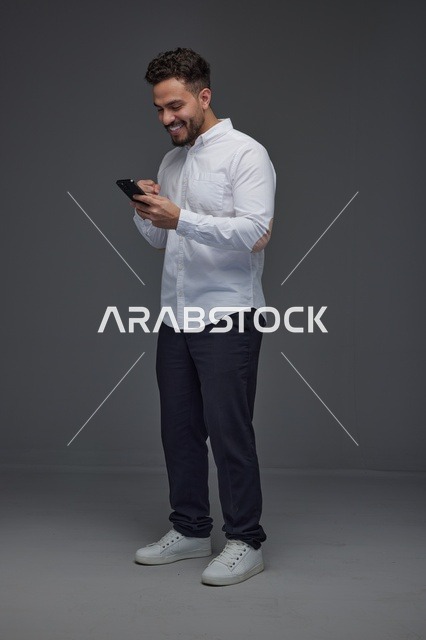 رجل سعودي يستخدم الهاتف الذكي بخلفية رمادية