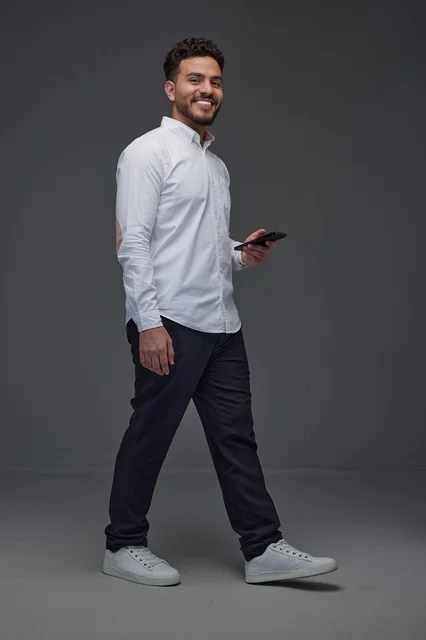 Saudi Man Walking with Smartphone in Gray Studio