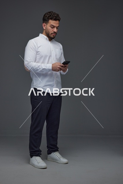 Saudi Man Using Smartphone on Gray Studio Background