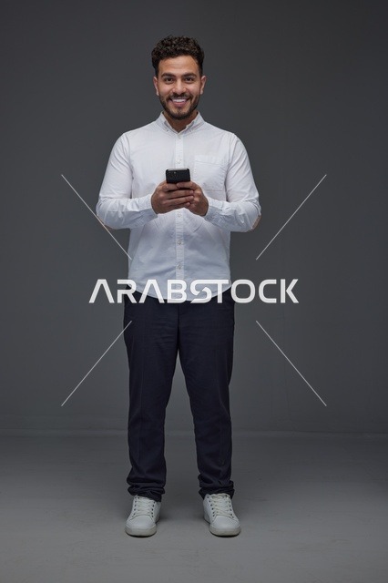 Saudi Man Using Smartphone Against Grey Studio Background