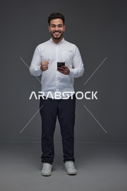 رجل سعودي يستخدم الهاتف الذكي ويحتفل بالنجاح