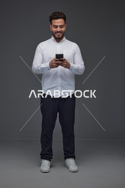 رجل سعودي يستخدم الهاتف الذكي بخلفية رمادية