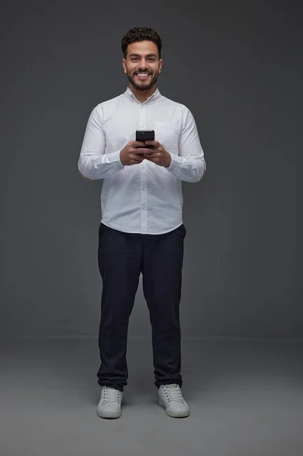 Smiling Saudi Man Using Smartphone on Grey Studio Background