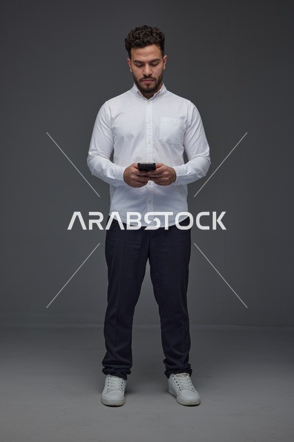 Saudi Man Using Smartphone on Grey Studio Background