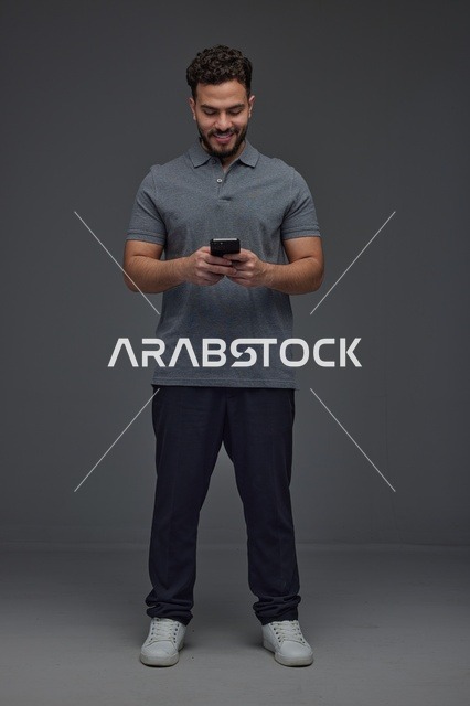 Saudi Man Using Smartphone on Grey Studio Background