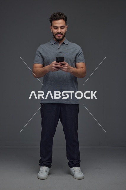 Saudi Man Using Smartphone on Grey Background