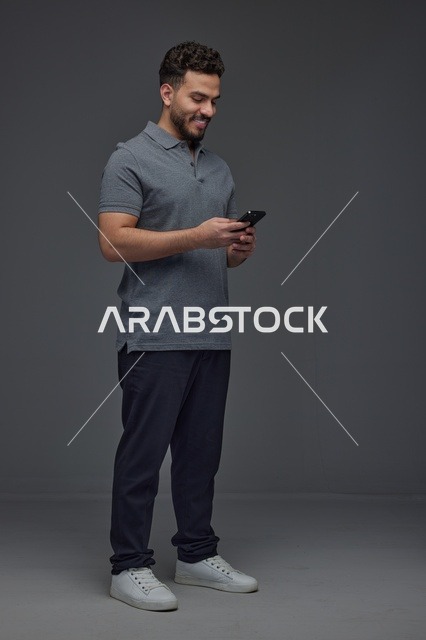 Saudi Man Using Smartphone on Gray Studio Background