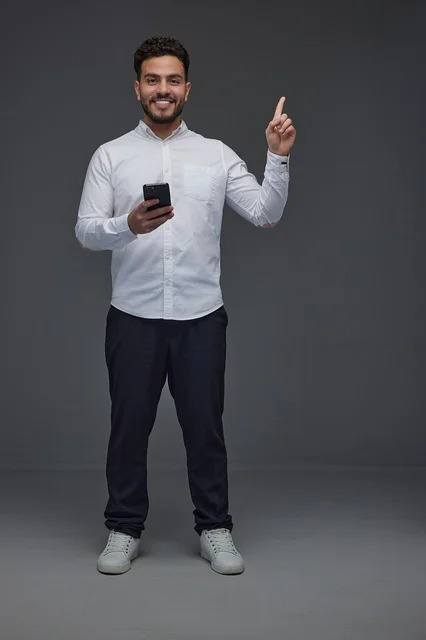 Saudi Man Holding Smartphone and Pointing Upwards