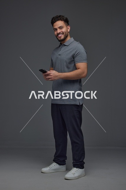 رجل سعودي يستخدم الهاتف الذكي بخلفية رمادية