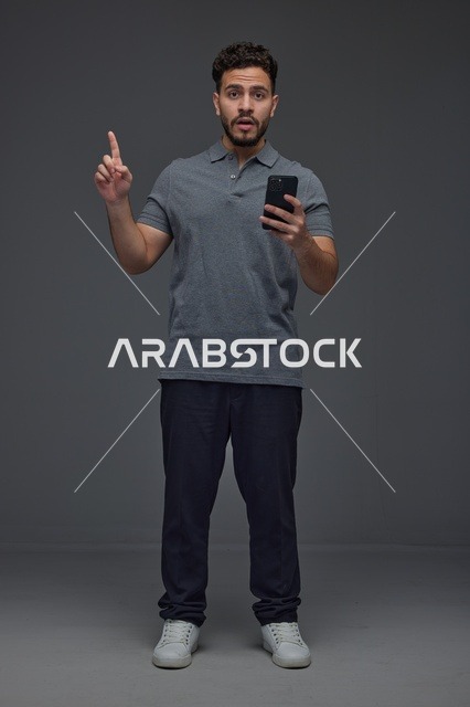 رجل سعودي يحمل هاتف ذكي ويشير للأعلى