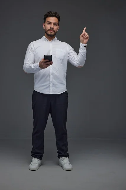 Saudi Man Holding Smartphone and Pointing Upwards