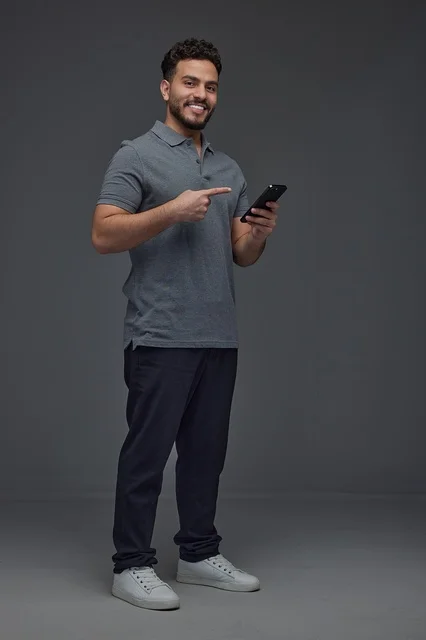 Saudi Man Pointing at Smartphone on Gray Background Saudi Man Pointing at Smartphone on Gray Background