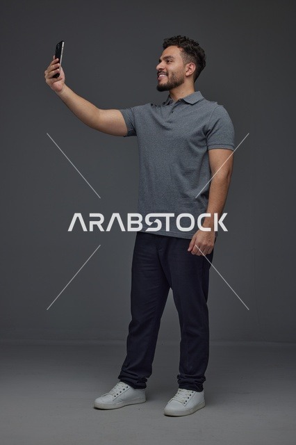 رجل سعودي يلتقط صورة سيلفي بالهاتف الذكي في استوديو