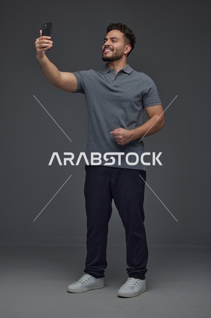 رجل سعودي يلتقط صورة سيلفي بالهاتف في استوديو عصري