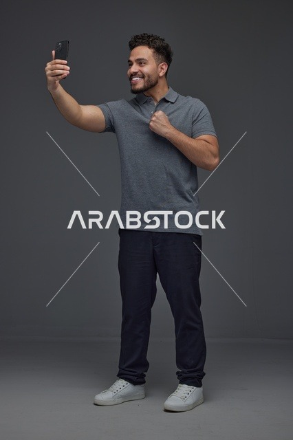 رجل سعودي يلتقط صورة سيلفي بالهاتف الذكي في الاستوديو