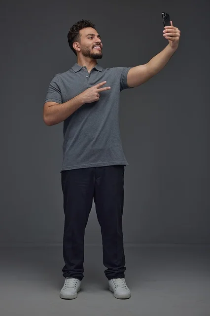 Saudi Man Taking Selfie with Smartphone Against Grey Background
