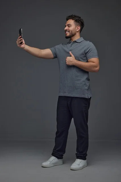 Saudi Man Taking Selfie with Thumbs Up on Grey Background