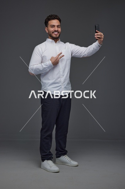 رجل سعودي يلتقط صورة سيلفي بالهاتف الذكي في استوديو
