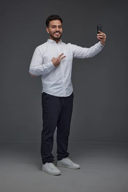 Saudi Man Taking Selfie with Smartphone in Grey Studio