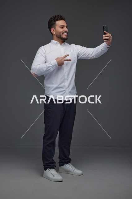 رجل سعودي يلتقط سيلفي بالهاتف الذكي في الاستوديو