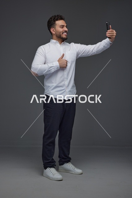 رجل سعودي يلتقط صورة سيلفي بالهاتف الذكي مع إشارة إعجاب