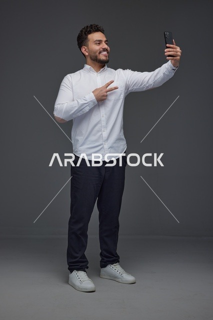 رجل سعودي يلتقط سيلفي بالهاتف في الاستوديو