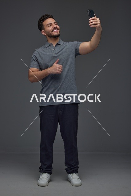 رجل سعودي يلتقط سيلفي بالهاتف مع إيماءة الإبهام