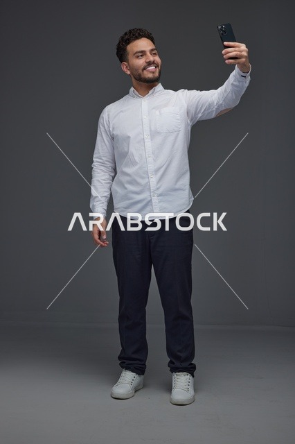 رجل سعودي يلتقط صورة سيلفي بالهاتف في الاستوديو