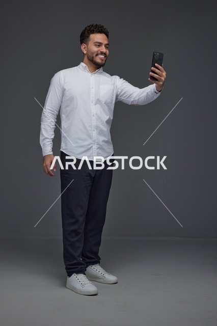 رجل سعودي يلتقط صورة سيلفي بالهاتف في الاستوديو