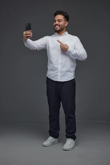 Saudi Man Taking Selfie with Smartphone on Gray Background