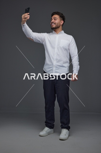 رجل سعودي يلتقط صورة سيلفي بالهاتف في الاستوديو
